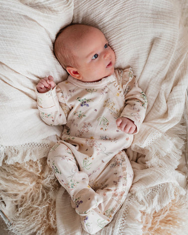 Newborn baby in a floral outfit lying on soft fabric